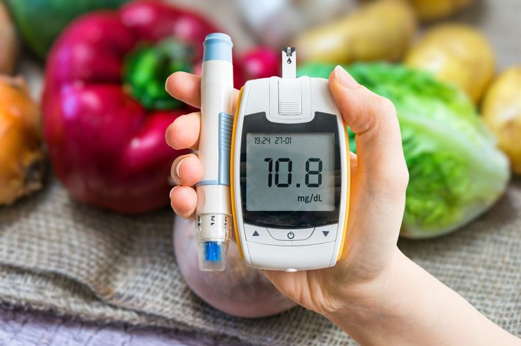 Blood sugar monitor in front of vegetables Managing Your Blood Sugar