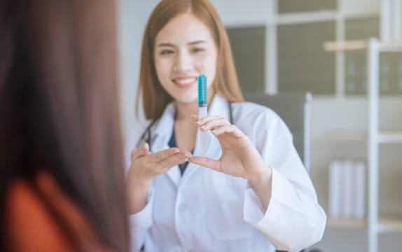 Pharmacist holding up vaccine syringe