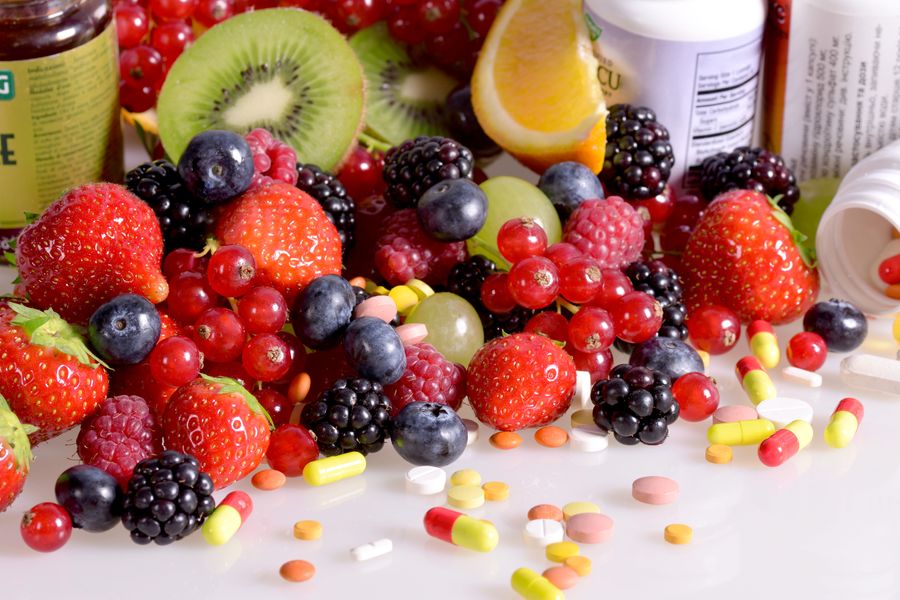 Vitamins next to fruits and berries Vitamins + Supplements