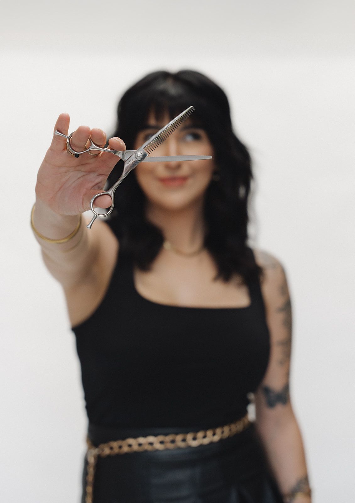 A Haus of FIDI stylist holding scissors, symbolizing expert haircut and styling services in Pensacola, Florida. Stylist holding scissors at Haus of FIDI Pensacola