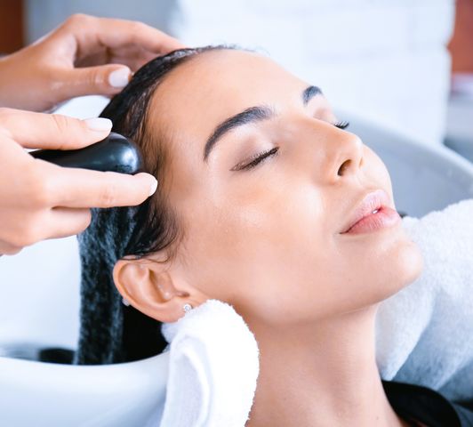 Woman relaxing during a hair wash and scalp massage at a salon, representing a salon gift card experience Salon Gift Card Experience – Hair Wash & Scalp Massage