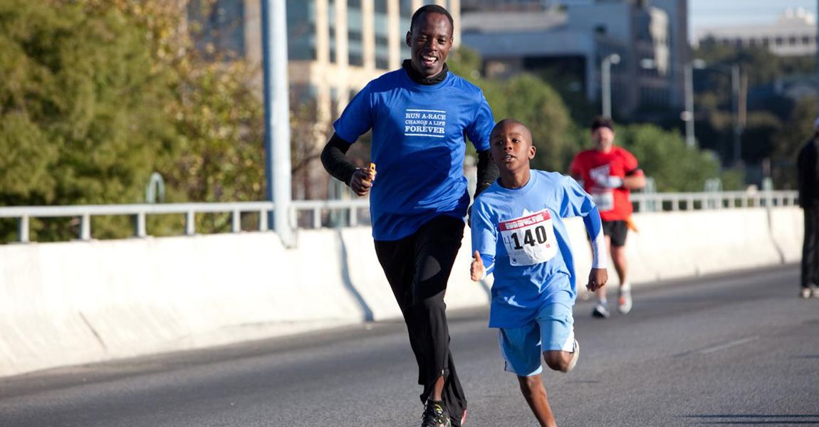 Gilbert Tuhabonye running with a child at Run for the Water