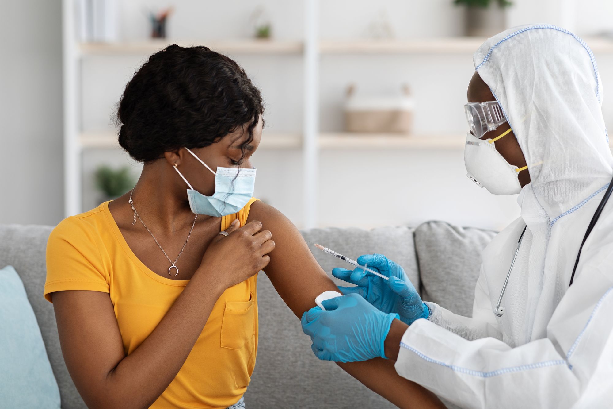 African american lady in face mask getting injection at home