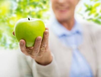 close-up-of-senior-woman-hand-holding-green-apple-PBVTQX2.jpg