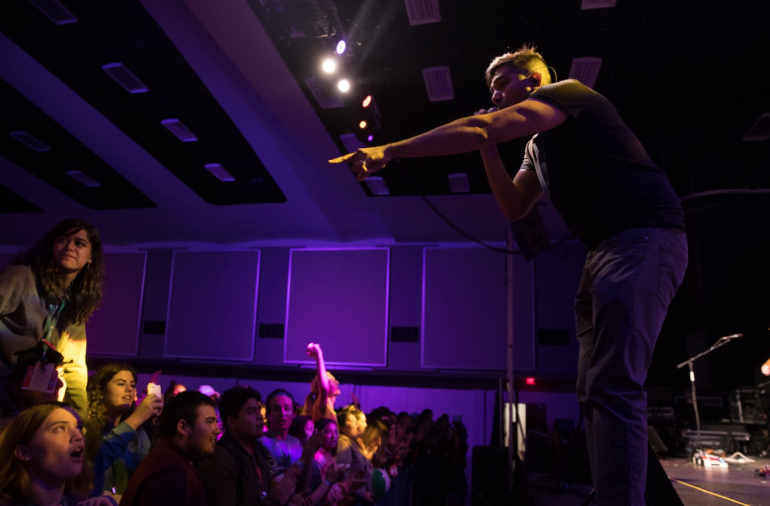 Performer singing to a crowd of teenagers at a conference