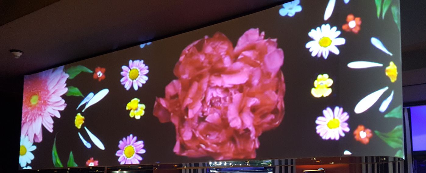Projection screen displaying floral design above bar at ATX event