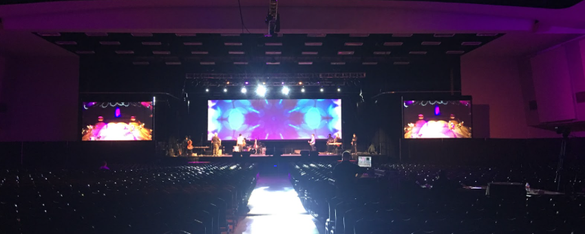 Large conference display with three screens and purple lighting