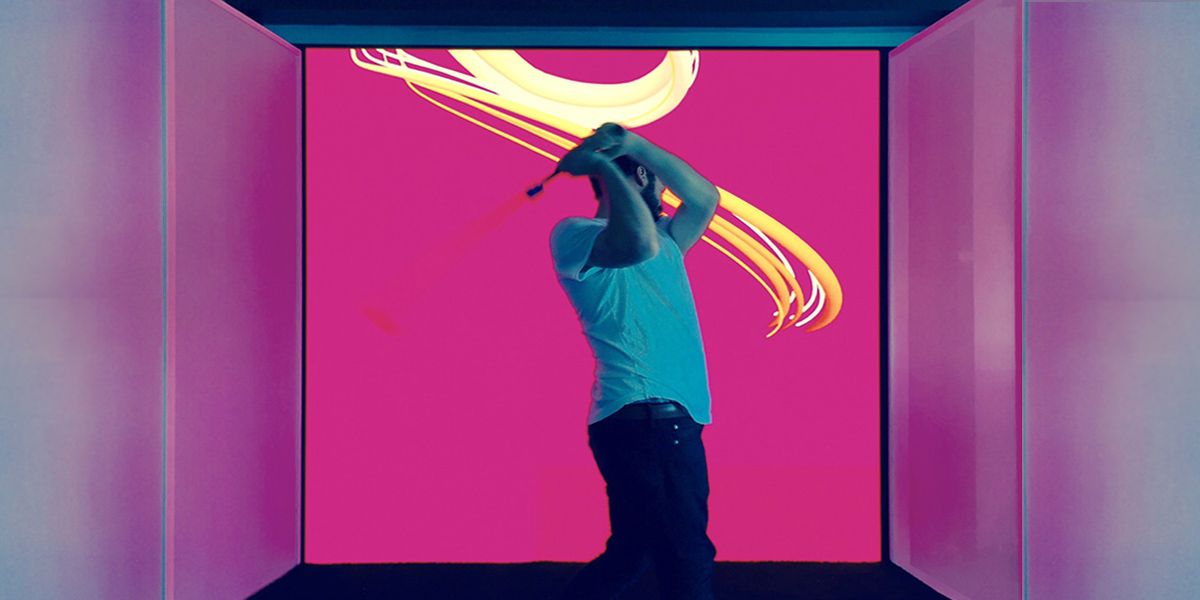 Man swinging golf club in front of pink LED video wall display 