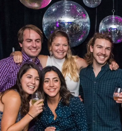 Group of people pictured at a party with disco balls in the background