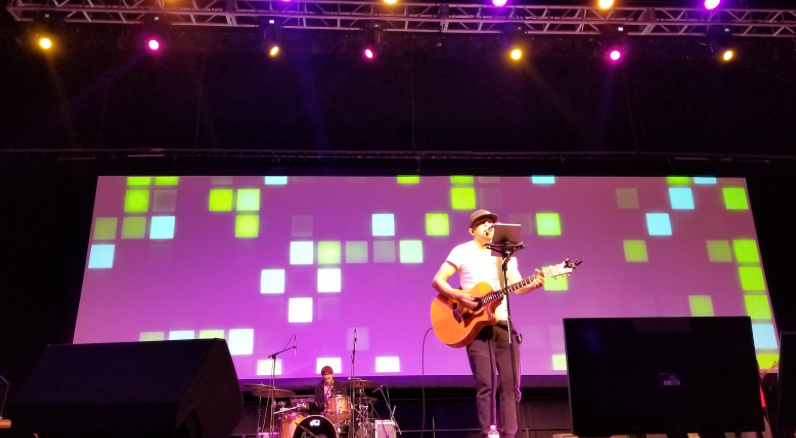 Man with acoustic guitar performing at conference