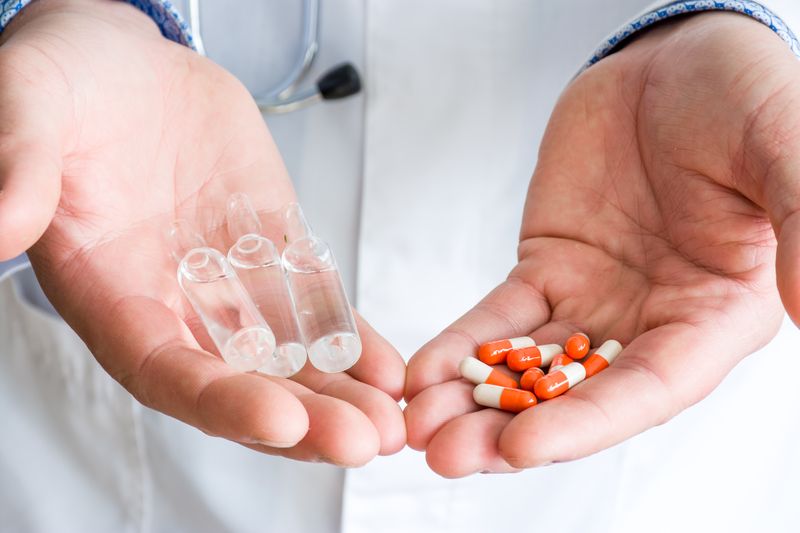 Image of healthcare professional holding out two kinds of medications. Medication Therapy Management