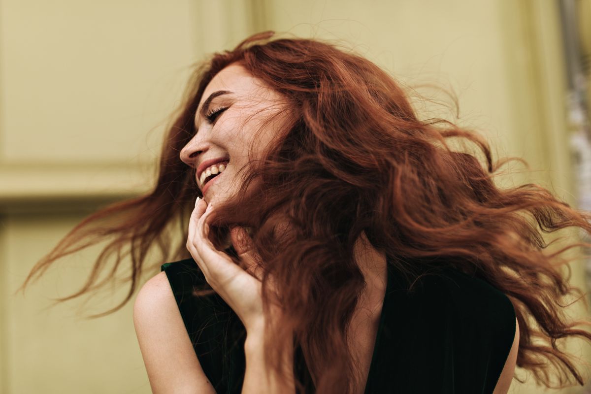 curly-woman-posing-outside-and-laughing-85LNH7K.jpg