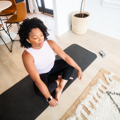 Woman sitting on yoga mat at home with closed eyes relaxing.png