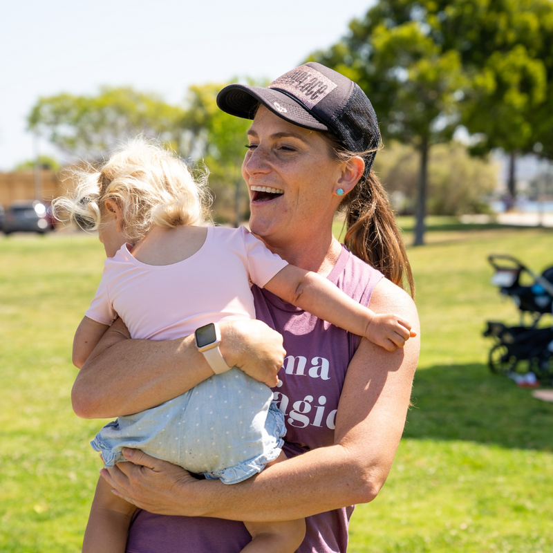 Mom holding young child smiling outdoors at a fit for mom Stroller Strides class.png