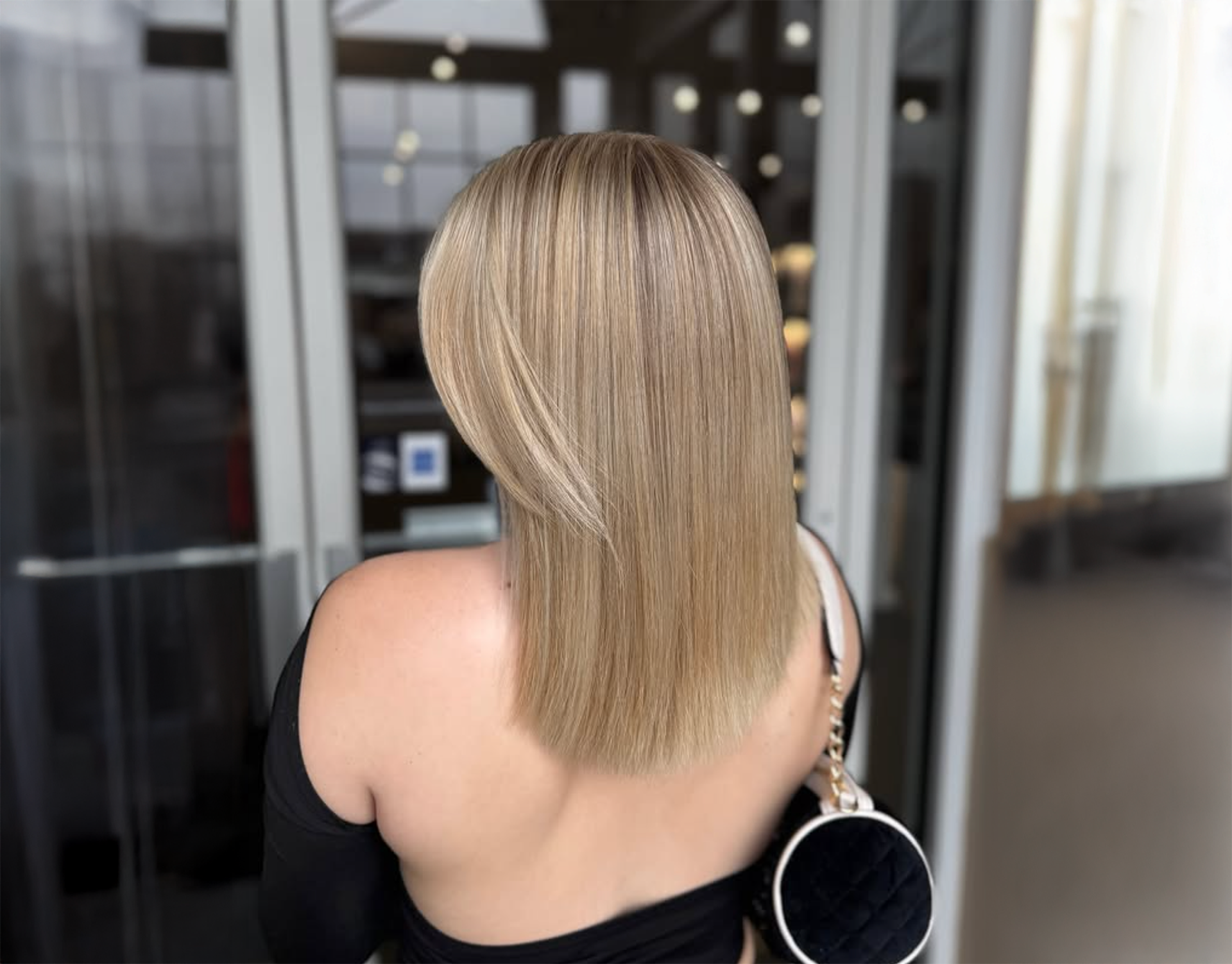 image of woman facing a window, showcasing back of seamless blonde hair seamless blonde look