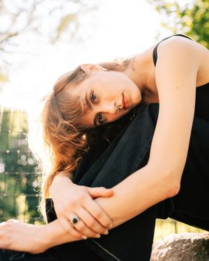 woman with short blonde hair sitting on a rock outside facing camera moody photo of woman sitting outside