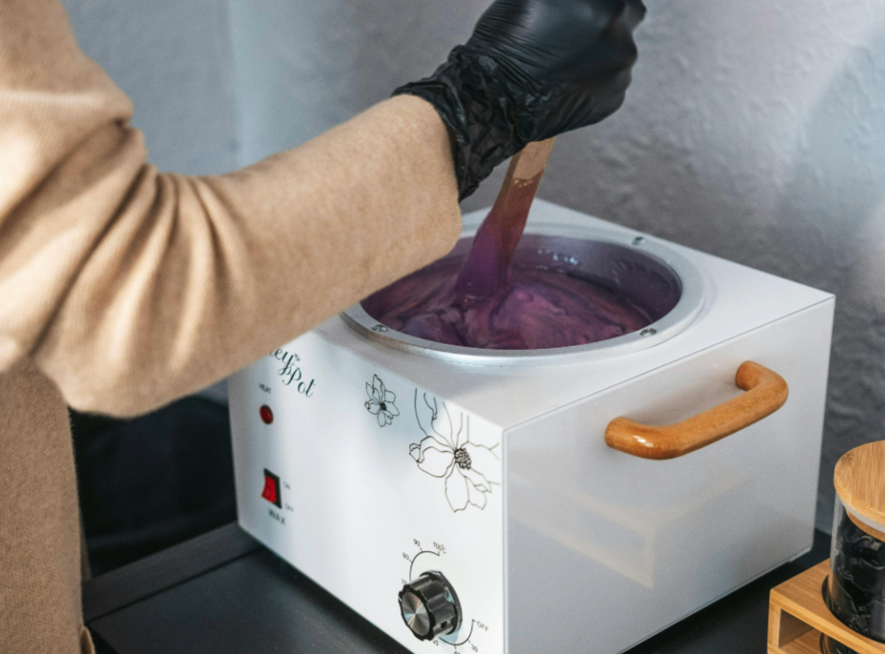 Waxer mixing heated wax with glove on Waxing Image