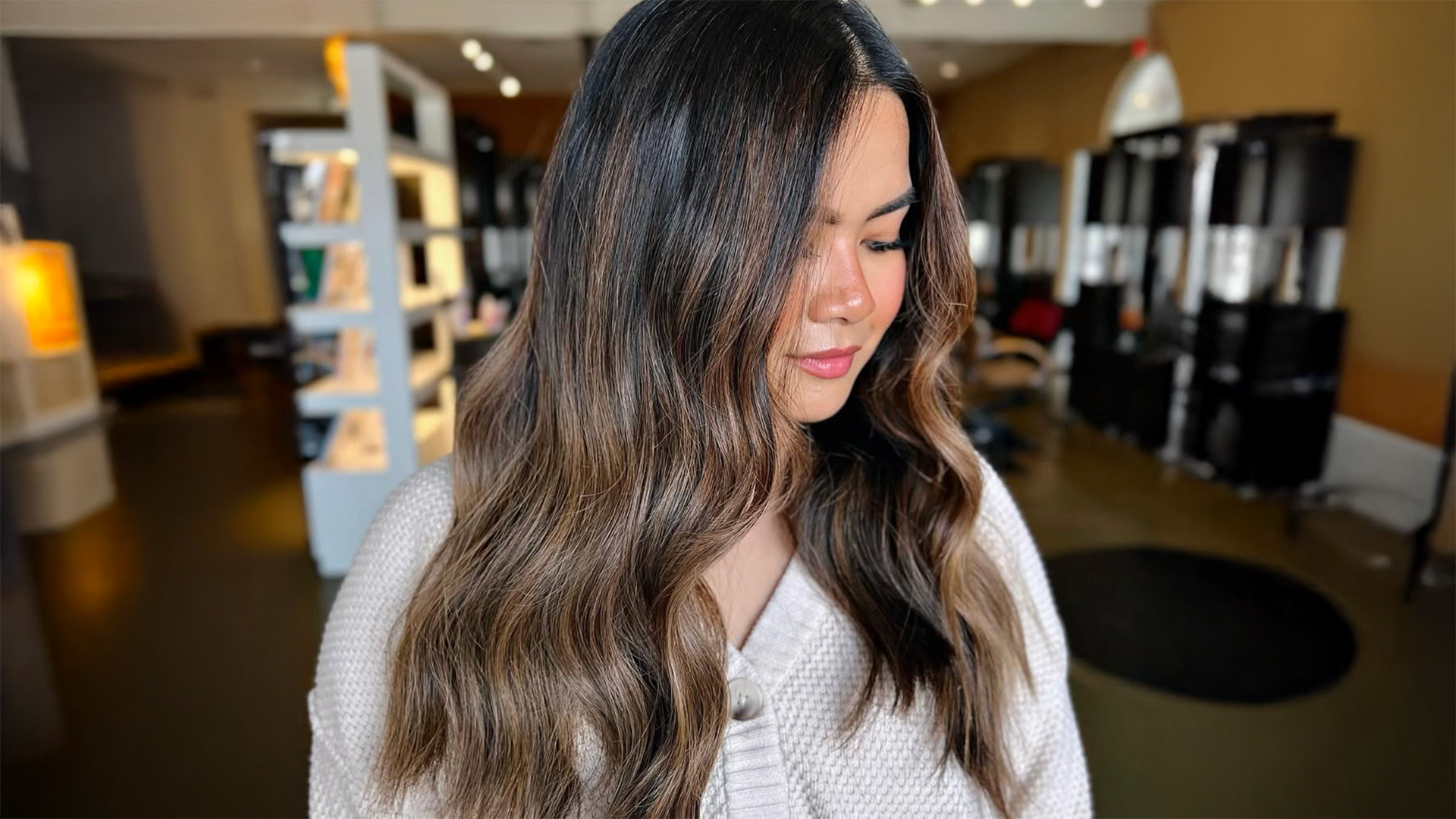 woman standing in Salon 01 showcasing long brunette balayage hair Image of a brunette balayage
