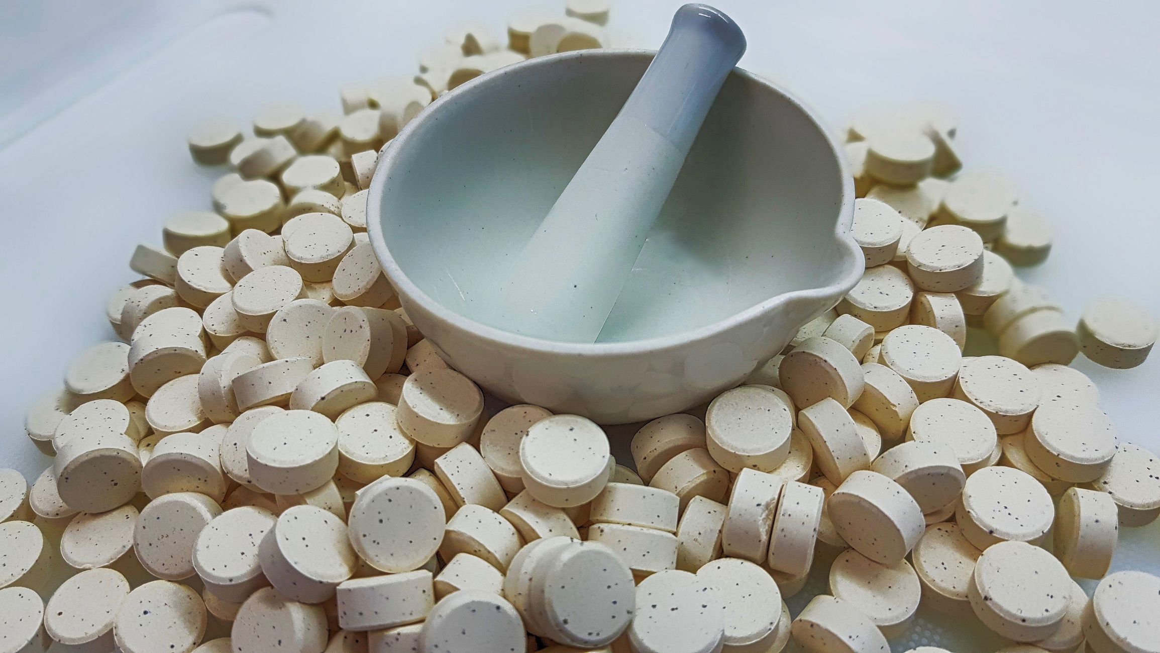 mortar and pestle sitting next to spilled medications. Compounding